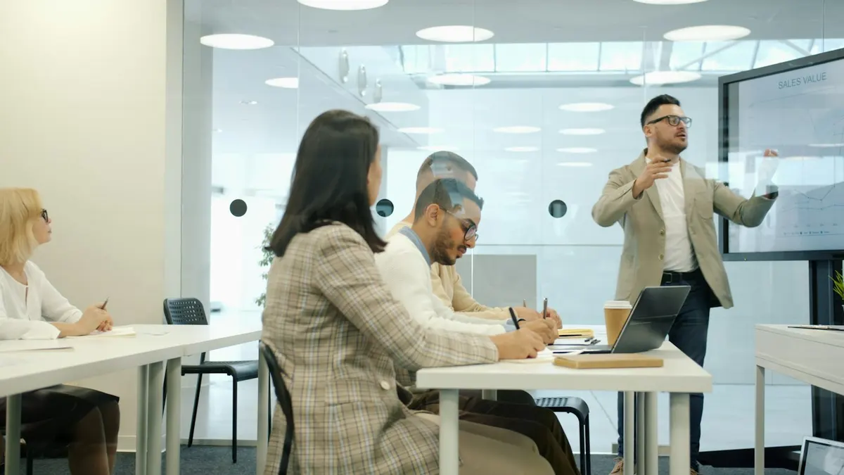 Formateur animant une session de formation devant un groupe de collaborateurs en salle