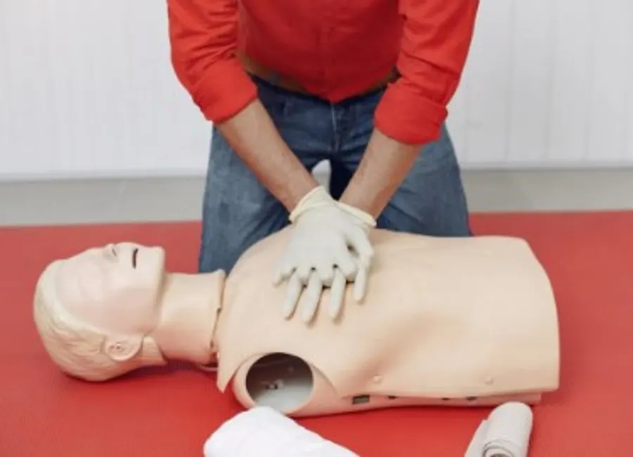 Formation SST : mise en pratique du massage cardiaque sur un mannequin avec gants